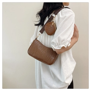 Détail du sac croissant marron tissé avec petit porte-monnaie assorti sur l'épaule