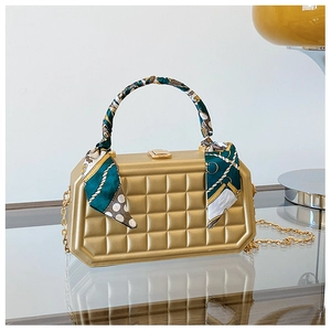 Detail of gold checkered box clutch bag featuring a silk scarf wrap and metal chain