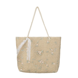 Straw tote bag with floral embroidery and white lace ribbon on a clean white background