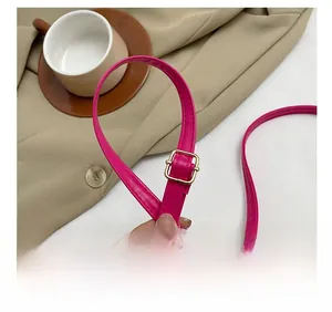 Détail de la bandoulière réglable en similicuir rose pêche avec boucle dorée mate