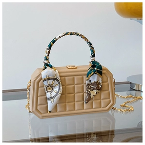 Detail of beige quilted box bag featuring a decorative silk scarf and gold chain strap