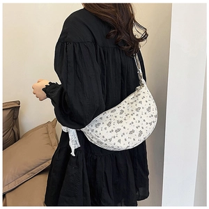 Floral canvas crescent bag with lace bow detail shown on shoulder in a stylish outfit