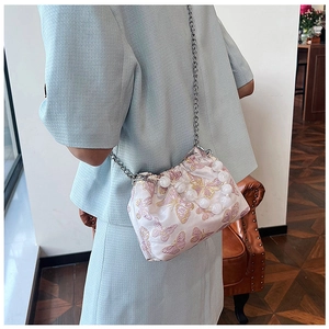 Pink satin dumpling bag with butterfly embroidery and pearl handle shown on shoulder