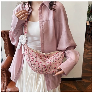 Detail of pink floral crescent bag featuring delicate white lace bow and matching strap