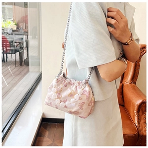Detail of pink satin bucket bag with gold butterfly embroidery and beaded handle