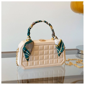 Detail of octagonal cream box bag with waffle texture and silk scarf wrapped handle