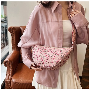 Detailed view of pink floral crescent bag worn across the body with matching strap