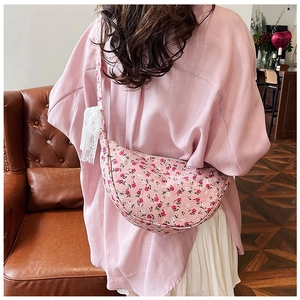 Detailed view of floral canvas half-moon crossbody bag with lace bow and strap