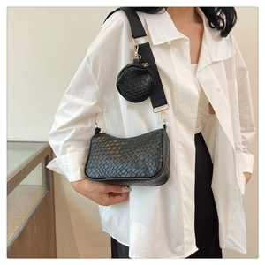 Détail du sac baguette noir tressé avec petite pochette ronde sur la bandoulière large