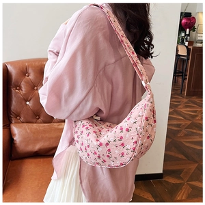 Detailed view of pink floral crescent hobo bag with pleated texture worn over the shoulder