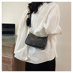 Détail du sac baguette noir tressé avec bandoulière large et petite pochette ronde