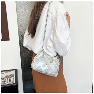 Detail of white silk bucket bag with blue butterfly embroidery and large bead handle