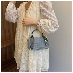 Detailed shot of grey plaid embossed handbag with silk scarf handle and gold chain strap