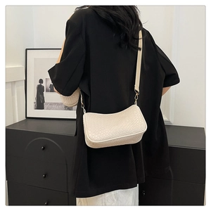 Gros plan sur la texture crocodile beige d'un sac sous le bras pour femme avec crochets dorés