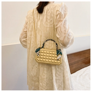Close-up of golden quilted box bag with floral silk scarf handle and chain strap