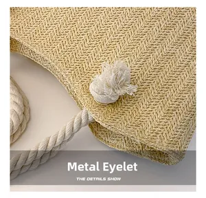 Detail of woven straw tote bag featuring cream cotton rope handle and metal grommet hardware