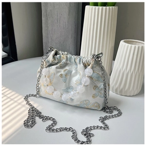 Detail of beaded handle and butterfly embroidery on a silk texture bucket bag