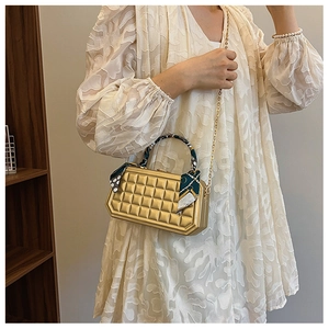 Detail of gold quilted box handbag with silk scarf handle and chain strap on model