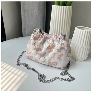 Detailed close-up of pink silk butterfly embroidery and elegant white beaded handle