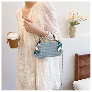 Detail of light blue checkered handbag with silk scarf handle and gold chain strap