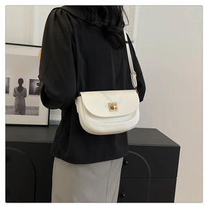 Sac besace blanc minimaliste avec fermoir doré porté par un mannequin de côté