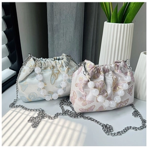 Close-up of butterfly embroidery detail on satin drawstring bags with pearl handles