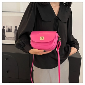 Détail du sac besace en cuir rouge rose avec boucle dorée et bandoulière réglable