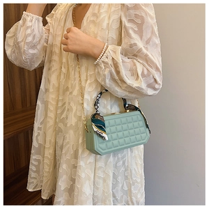 Close-up of light green plaid handbag with scarf-wrapped handle and gold chain strap