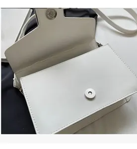 Detailed view of white quilted crossbody bag featuring silver magnetic snap button closure
