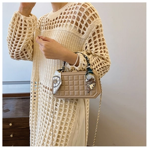 Detailed view of beige lattice box bag with silk scarf handle and gold chain strap