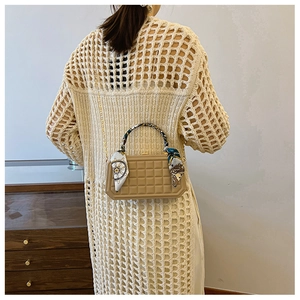 Detail of beige plaid handbag with silk scarf handle and elegant gold chain strap