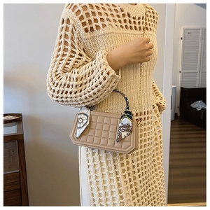 Detail of checkered beige handbag featuring a silk scarf handle and gold chain strap