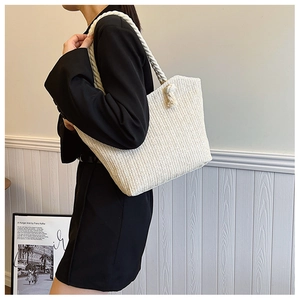 Detail of white straw tote bag showing woven texture and thick cotton rope handles