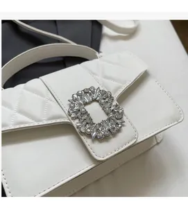 Close-up of white quilted leather bag with sparkling rectangular crystal buckle detail