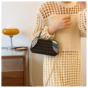 Detail of black plaid box handbag with silk scarf handle and golden chain strap