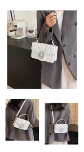 Detail of white quilted crossbody bag with luxury square rhinestone buckle and handle