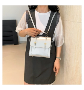 Detail of silver metallic leather square backpack with gold rivets and handle