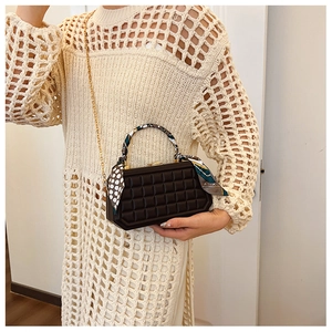 Detail of a brown checkered box handbag with a silk scarf handle and gold chain