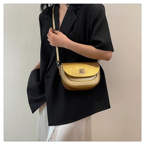 Modèle portant un sac selle doré métallisé avec forme demi-ronde et boucle carrée
