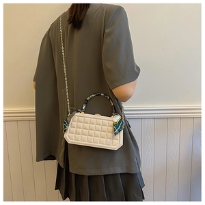 Detail of white lattice box handbag with printed silk scarf wrap on handle and gold chain