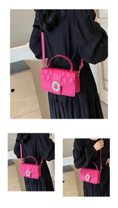 Detail of fuchsia quilted leather handbag featuring a crystal-encrusted round buckle ornament