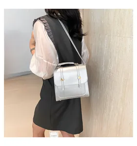 Silver metallic crossbody bag with gold round buckle shown on a model in a modern room