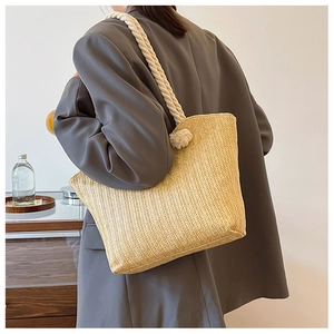 Detail of straw woven tote bag with white cotton rope handles and herringbone weave texture