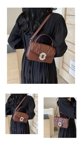 Detail of brown quilted shoulder bag featuring a sparkling rhinestone buckle and slim strap