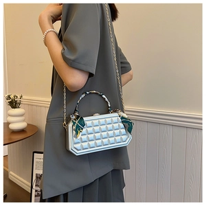 Detail of silver checkered hard shell box bag with silk scarf handle and gold chain strap