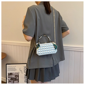 Close-up of silver quilted handbag with chain strap and scarf-wrapped handle detail