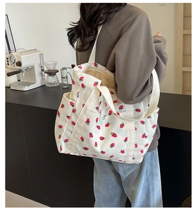 Gros plan détaillé d'un sac cabas en velours côtelé blanc avec motifs de fraises rouges