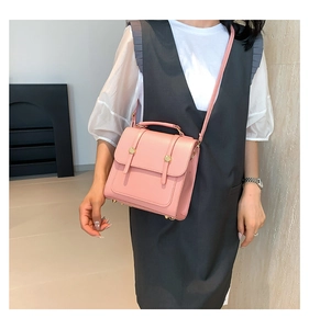 Detail of pink crossbody bag with top handle and gold buckles for elegant casual use