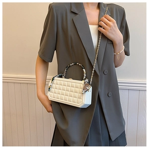 Detail of white checkered box bag with silk scarf wrapped handle and gold chain strap