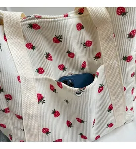 Gros plan d'un cabas en velours côtelé à fraises montrant la poche avant avec boucle métal